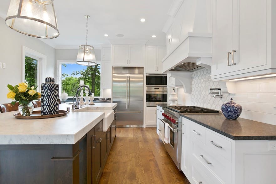 A kitchen with white cabinets and wood floors.