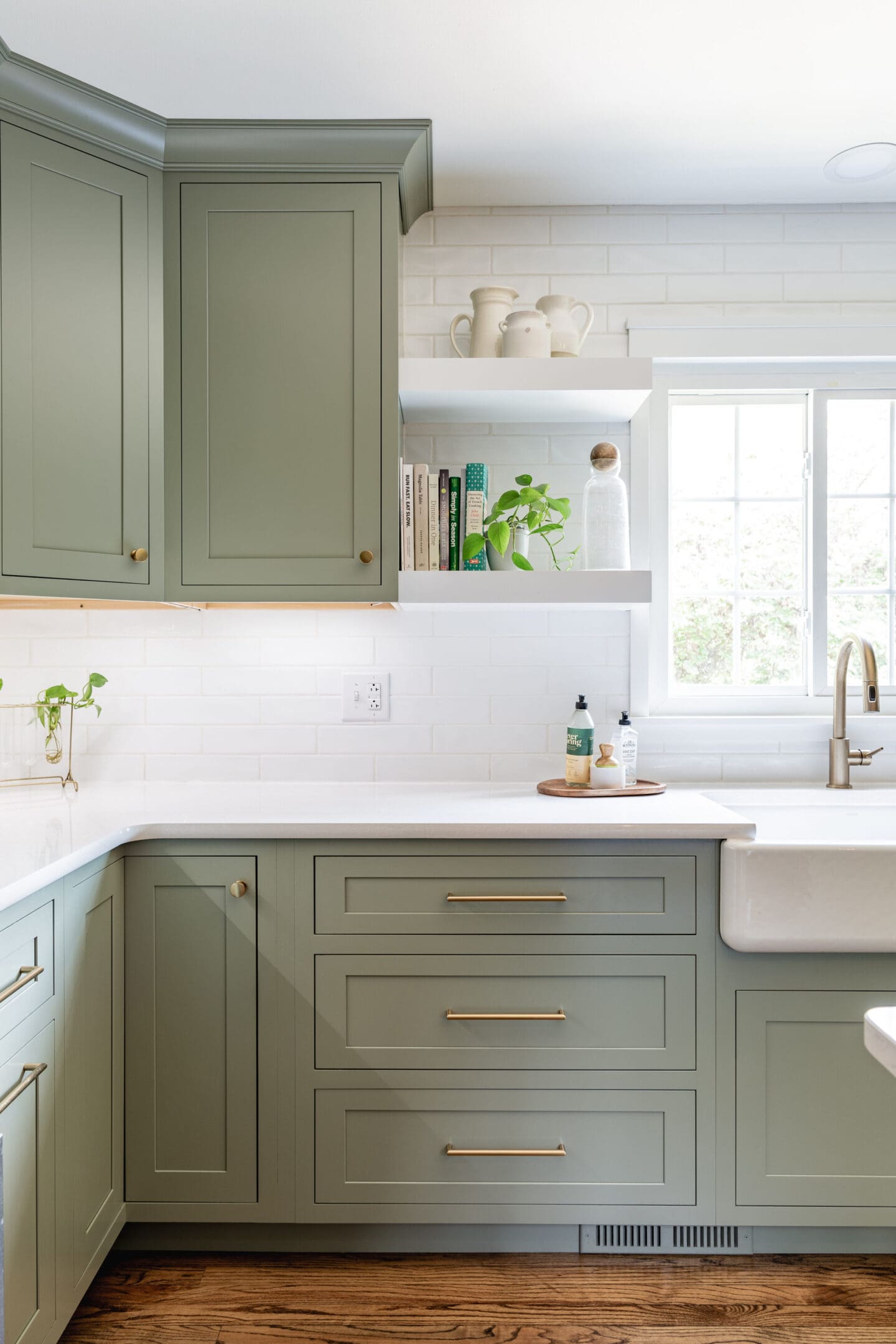 A kitchen with green cabinets and white counters.