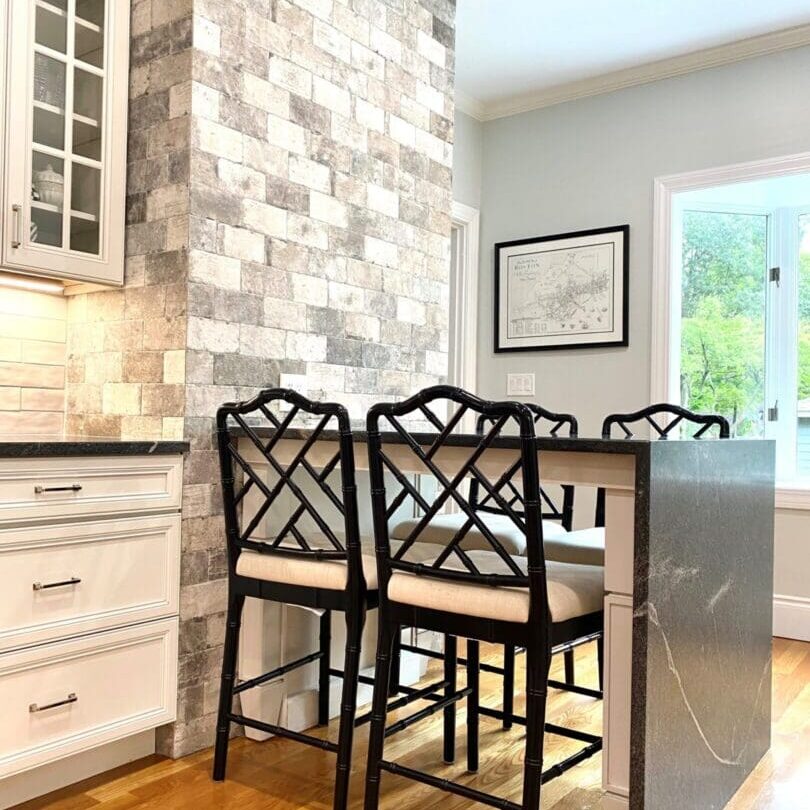 A kitchen with a counter and four chairs