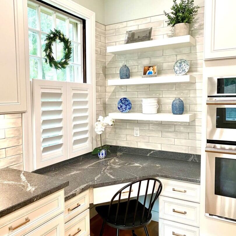 A kitchen with white cabinets and black counter tops.